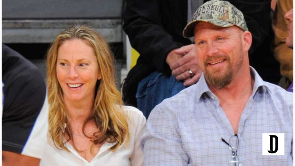 Kathryn Eurrhus, a blonde woman, smiles while sitting next to a bearded man in a plaid shirt and camo cap at a sports event